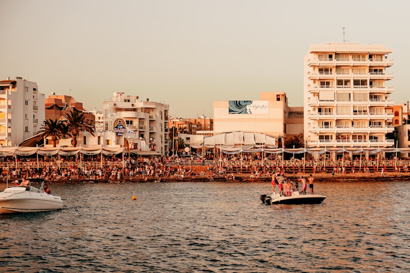 people riding on boat on sea near buildings during daytime